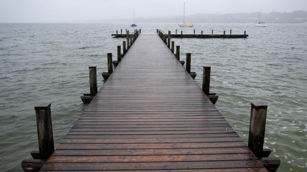 SYMBOLBILD - Dunkle Wolken ziehen über einen Steg