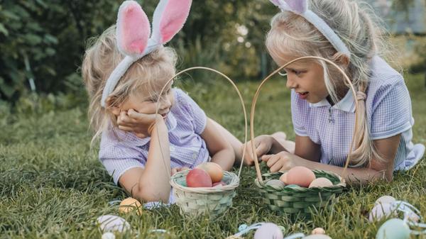Zwei Mädchen mit Hasenohren genießen eine Ostereie