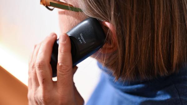 Eine Frau hält ein Festnetz-Telefon ans Ohr (geste