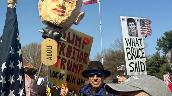 Demonstrierende halten einen Pappkopf der US-Heima