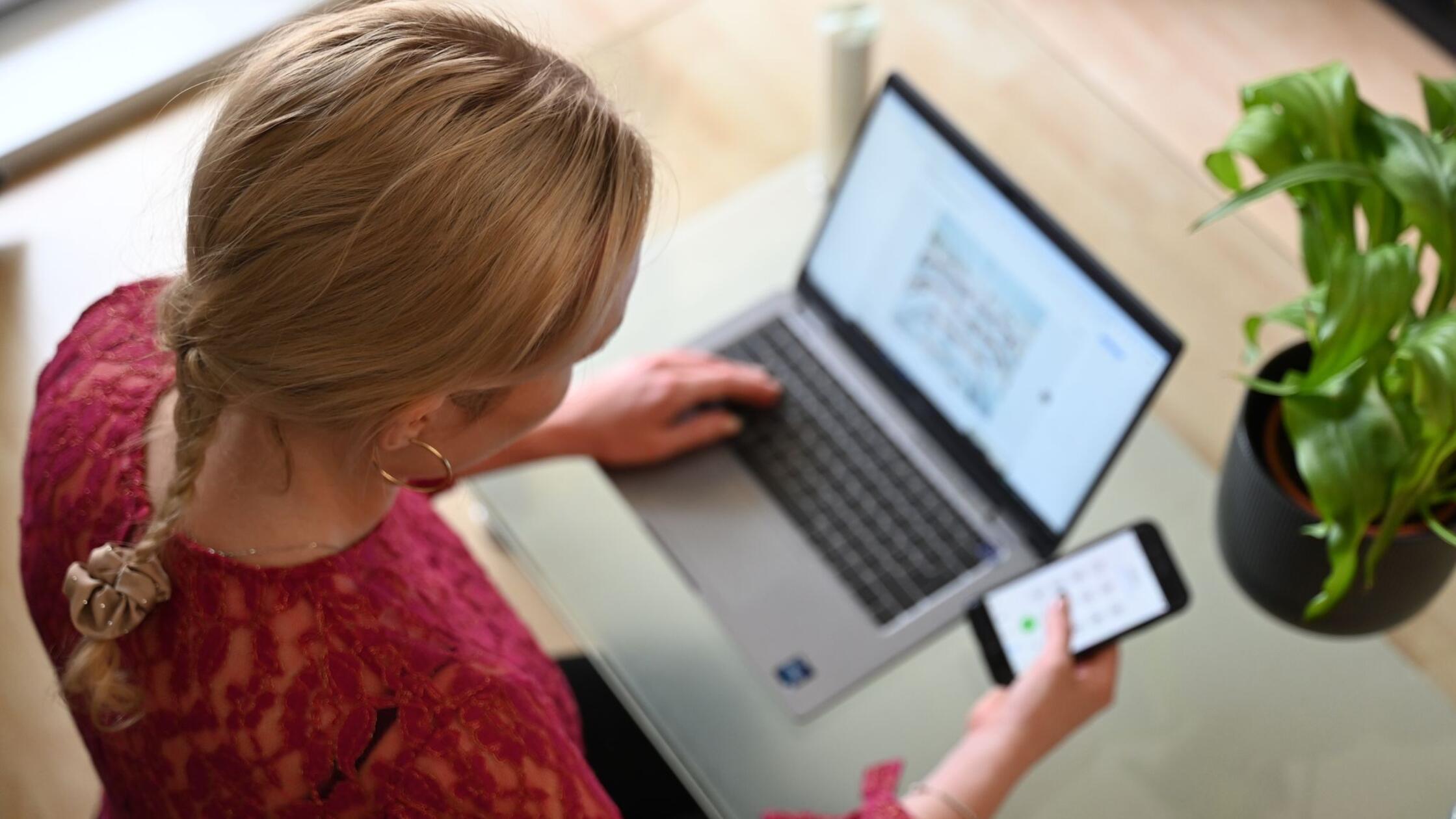 Eine Frau sitzt vor ihrem Laptop und schaut auf ih