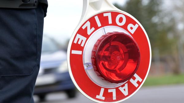 Ein Polizist hält eine Polizeikelle im Rahmen eine