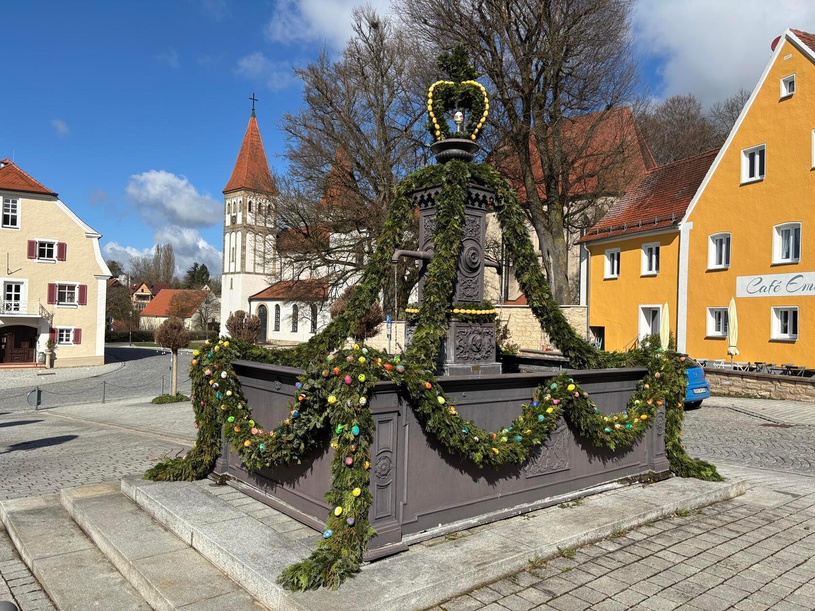 Der Osterbrunnen in Heidenheim mit dem Kloster im Hintergrund.