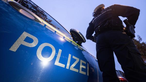 Eine Polizistin steht neben einem Polizeifahrzeug.