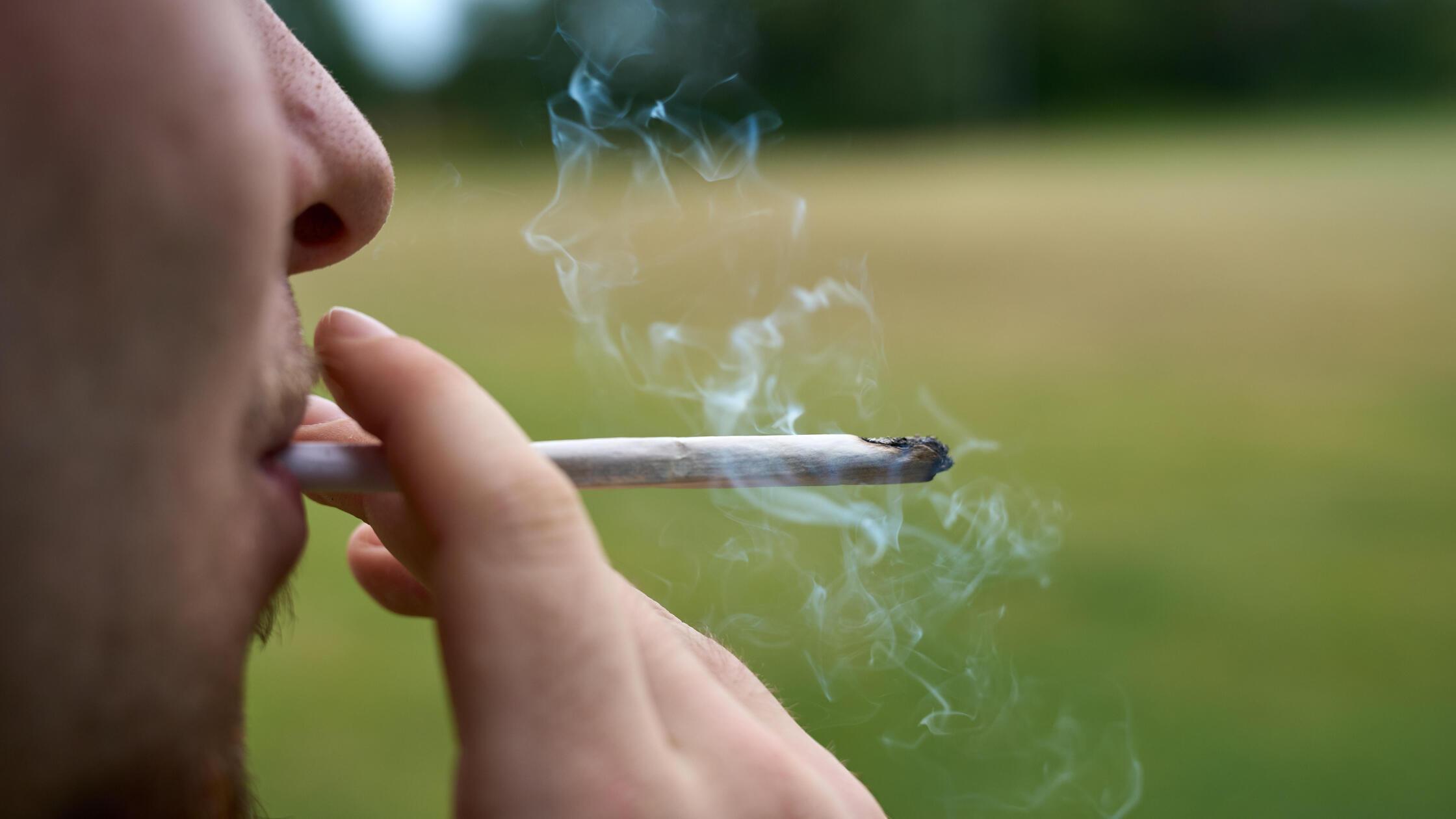 Ein Jugendlicher zieht an einem Cannabis Joint. Sy