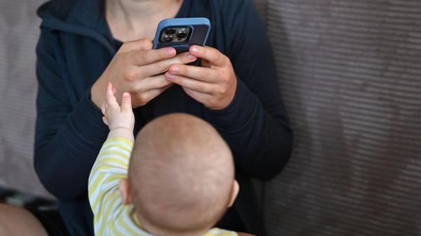 Ein Baby streckt die Hand nach dem Smartphone sein
