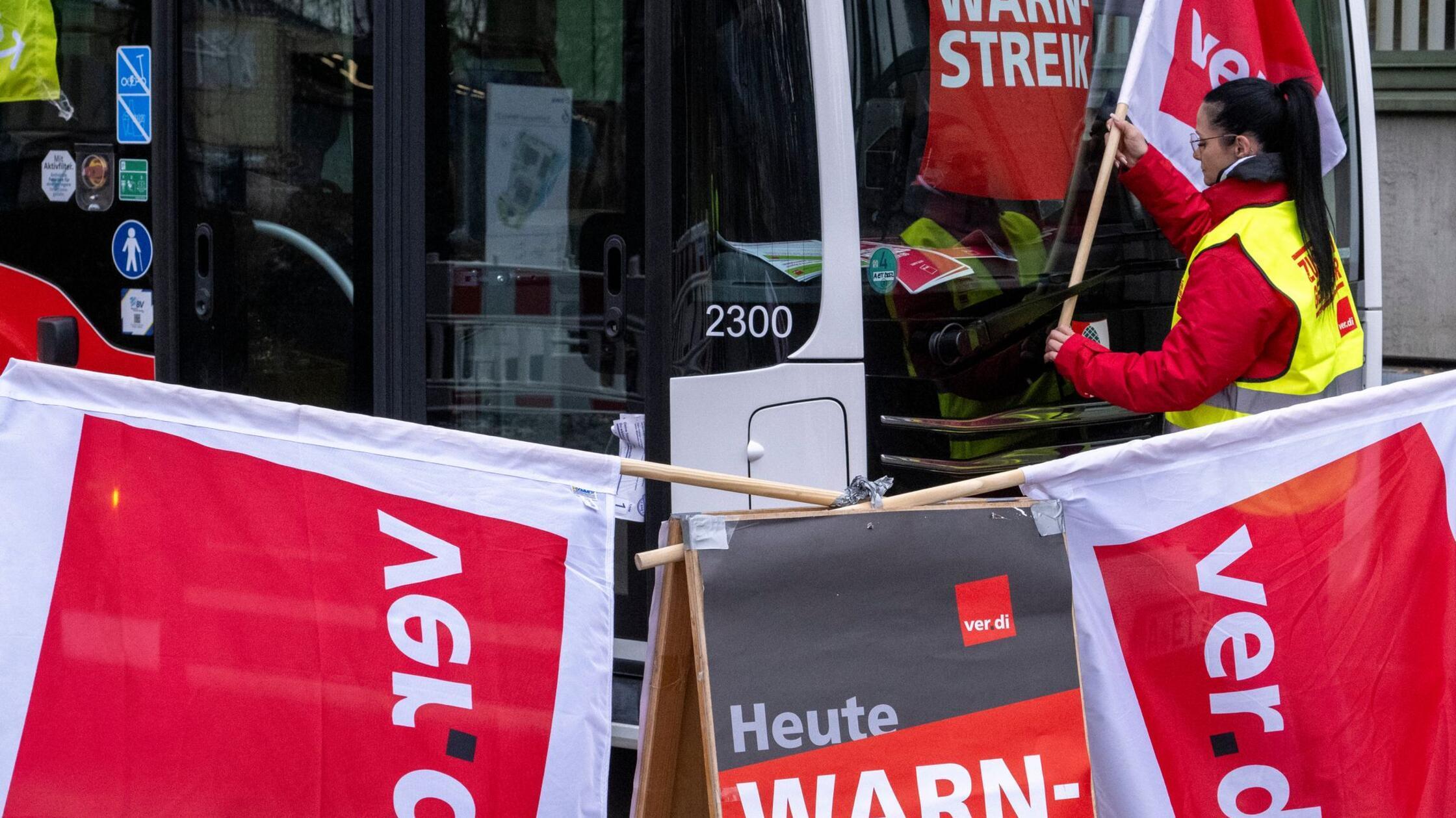 Eine Frau hängt eine Fahne der Gewerkschaft Verdi 