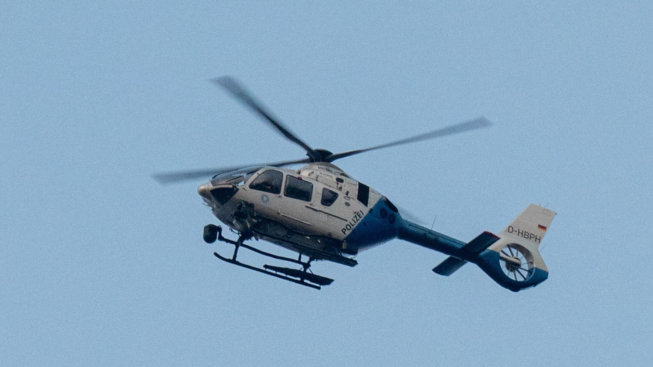 Ein Polizeihubschrauber fliegt über den Ortsrand. 