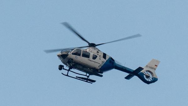 Ein Polizeihubschrauber fliegt über den Ortsrand.