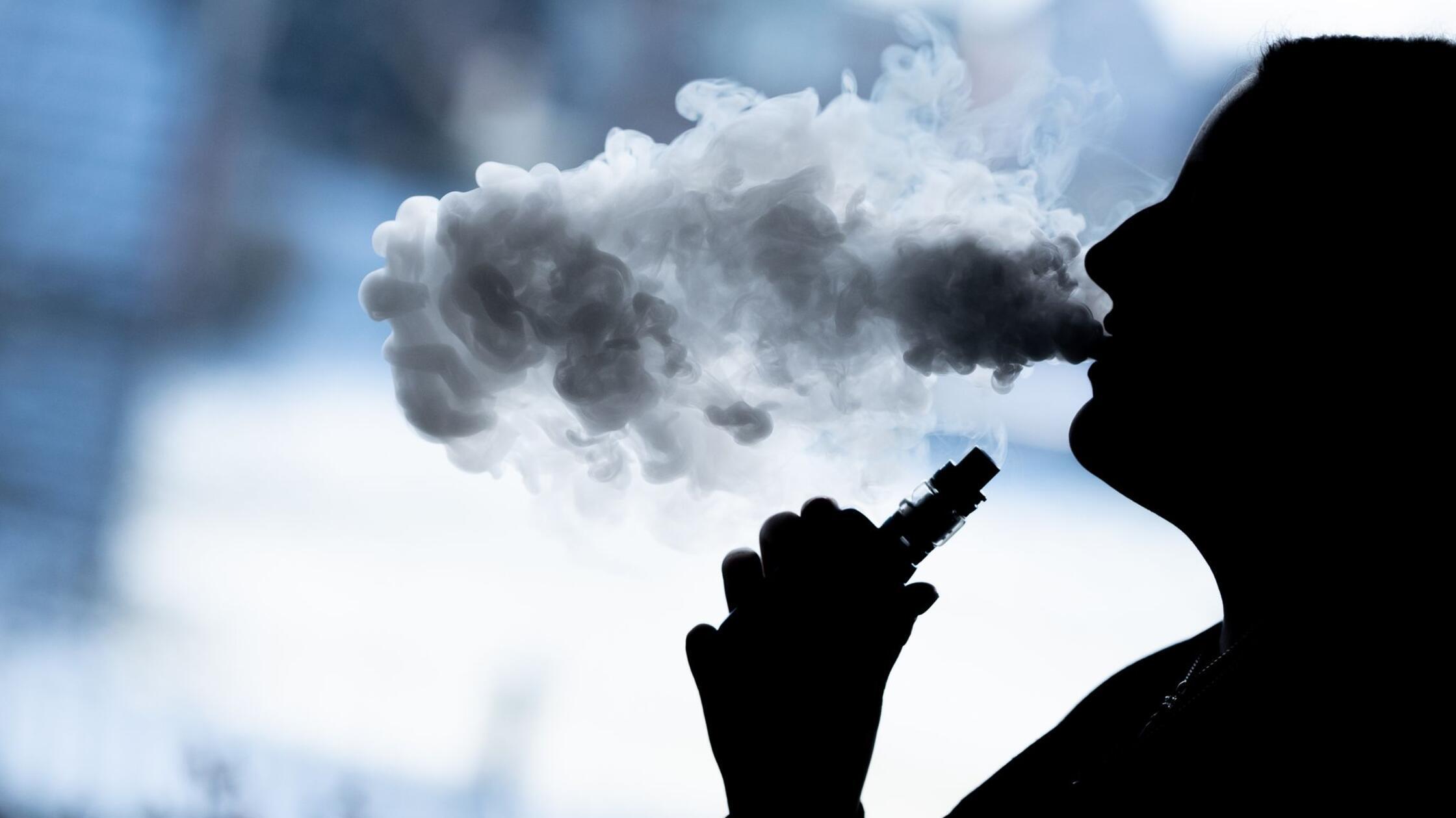 Eine junge Frau raucht mit einer E-Shisha und ist 