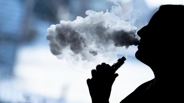 Eine junge Frau raucht mit einer E-Shisha und ist