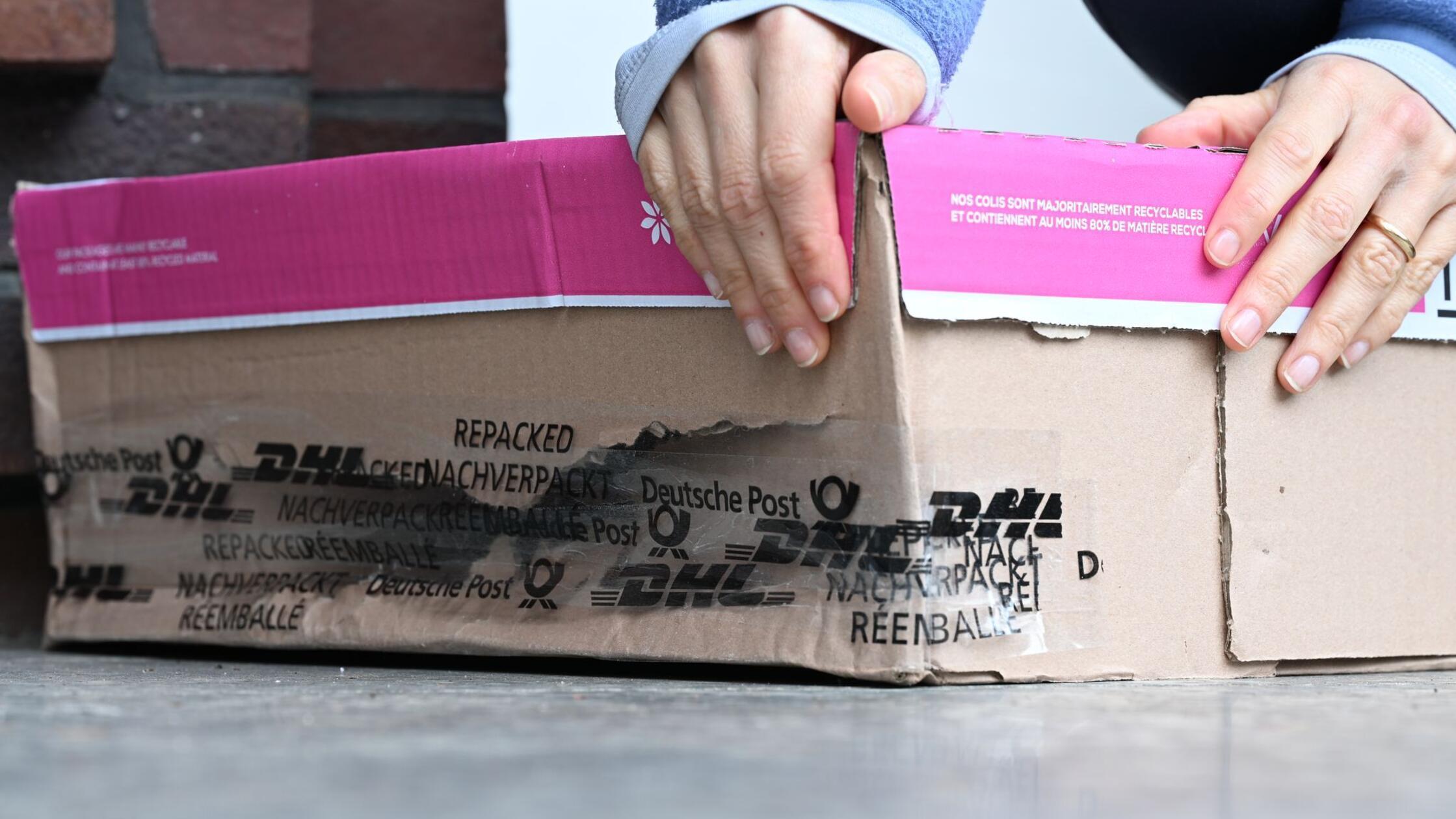 Eine Frau nimmt ein kaputtes Paket hoch, das vor i