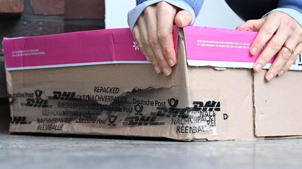 Eine Frau nimmt ein kaputtes Paket hoch, das vor i