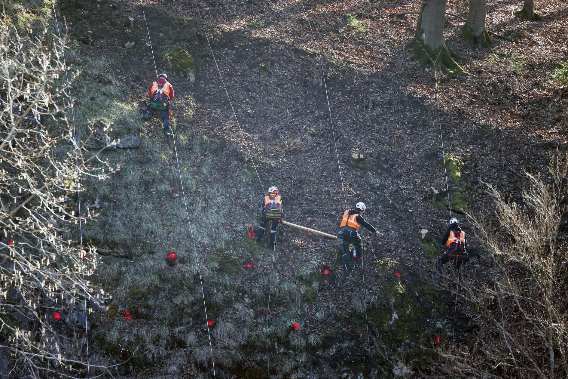 Vier an Kletterseilen gesicherte Mitarbeiter markieren die Stellen für die Bohrlöcher zur Felssicherung über einem Tunnel nahe Lungsdorf, einem Ortsteil von Hartenstein.