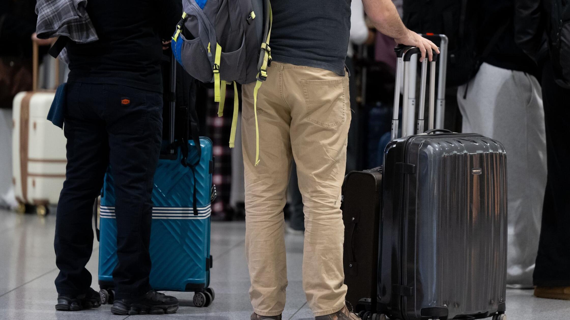 Passagiere stehen am Münchner Flughafen mit ihrem 