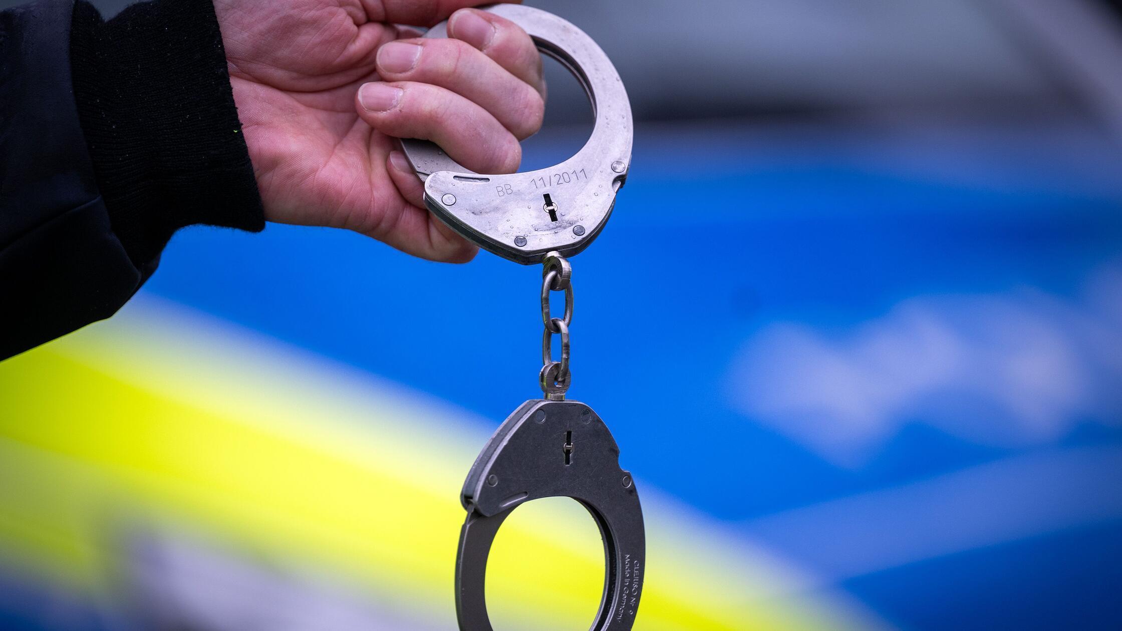 Ein Polizist hält ein Paar Handschellen. (zu dpa: 