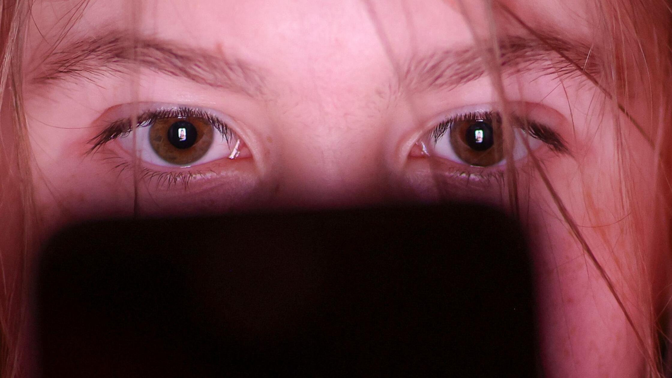 Ein Mädchen schaut auf einem Smartphone ein Make-u