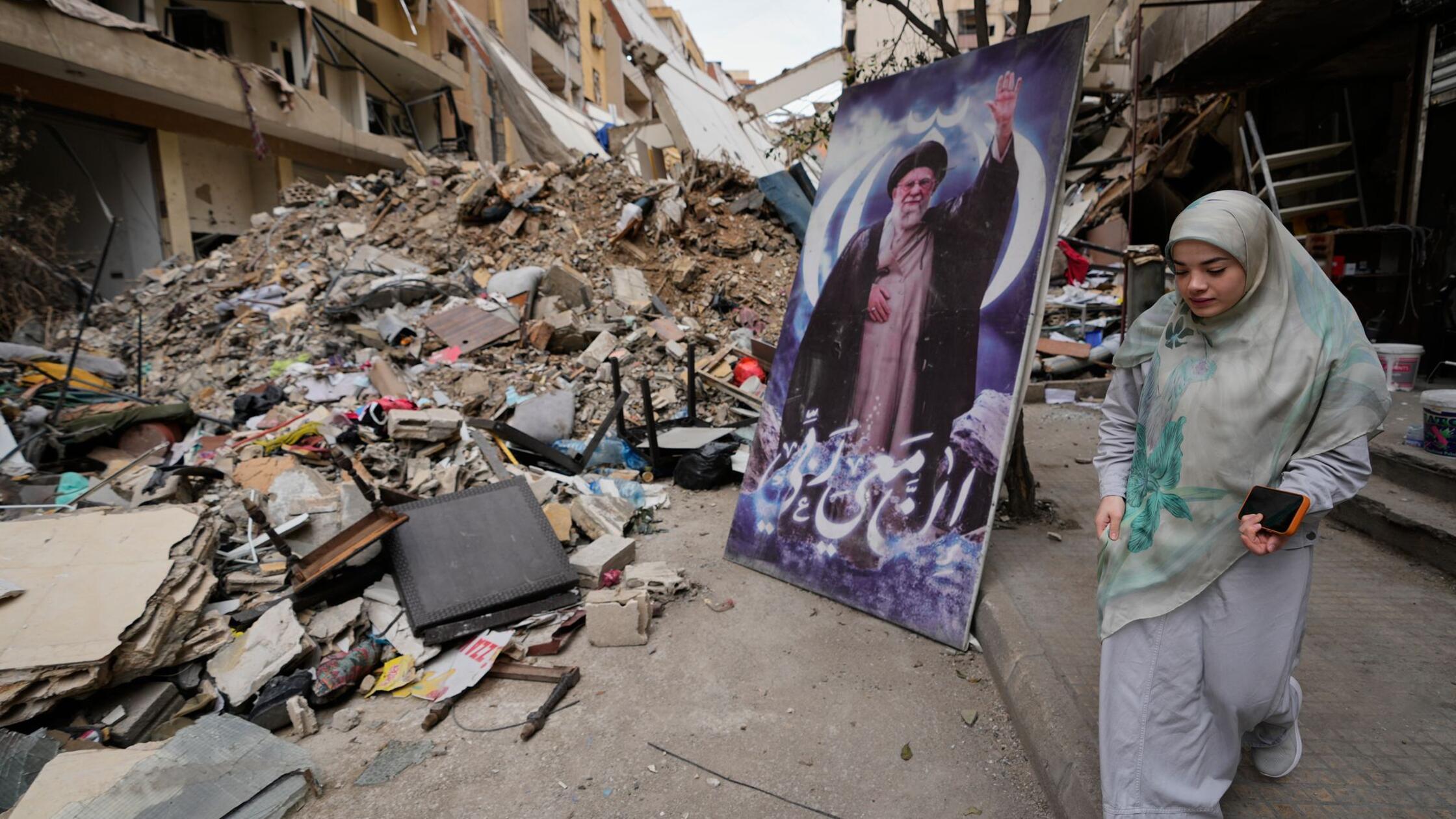 Eine Frau geht neben einem Plakat des verstorbenen