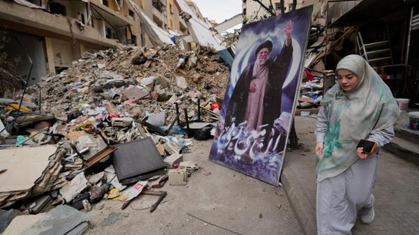 Eine Frau geht neben einem Plakat des verstorbenen