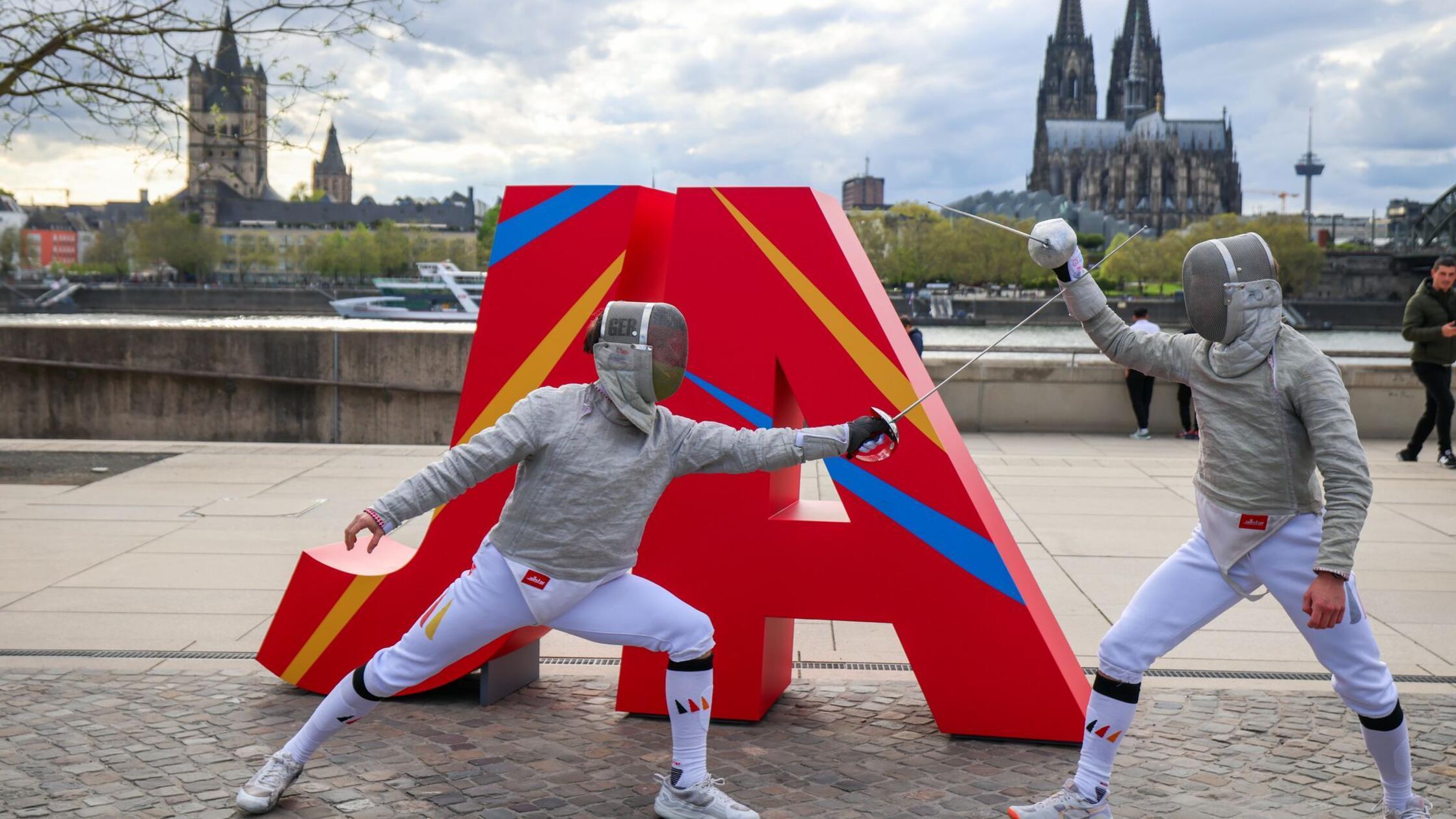 Zwei Fechter kämpfen vor dem Schriftzug „JA“ auf d