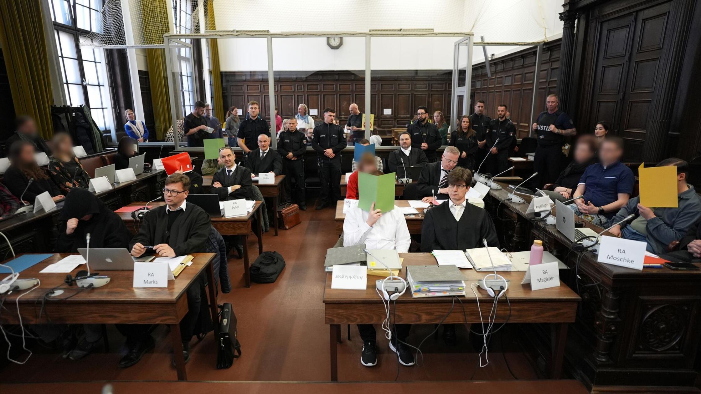 Die Angeklagten sitzen im Sitzungssaal im Strafjus