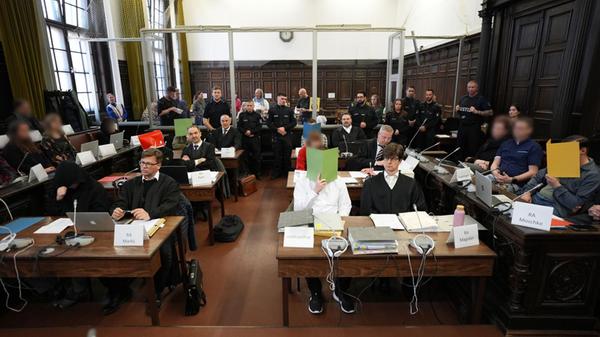 Die Angeklagten sitzen im Sitzungssaal im Strafjus