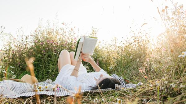 Woman lying on back and reading book in agricultur