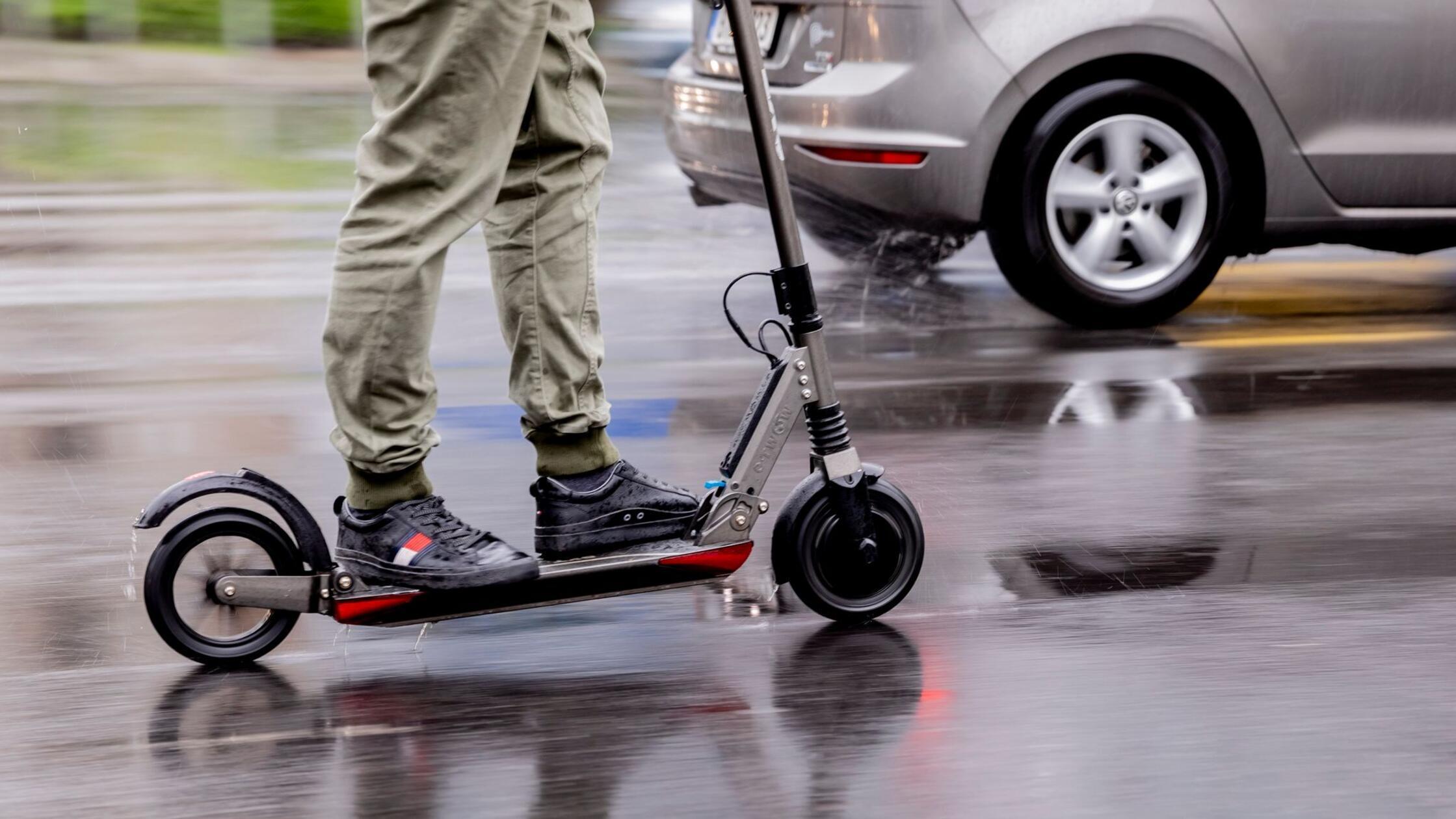 Ein Mann fährt mit einem E-Scooter auf der Straße.