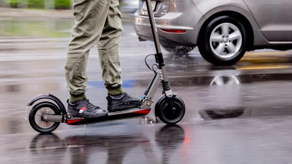 Ein Mann fährt mit einem E-Scooter auf der Straße.