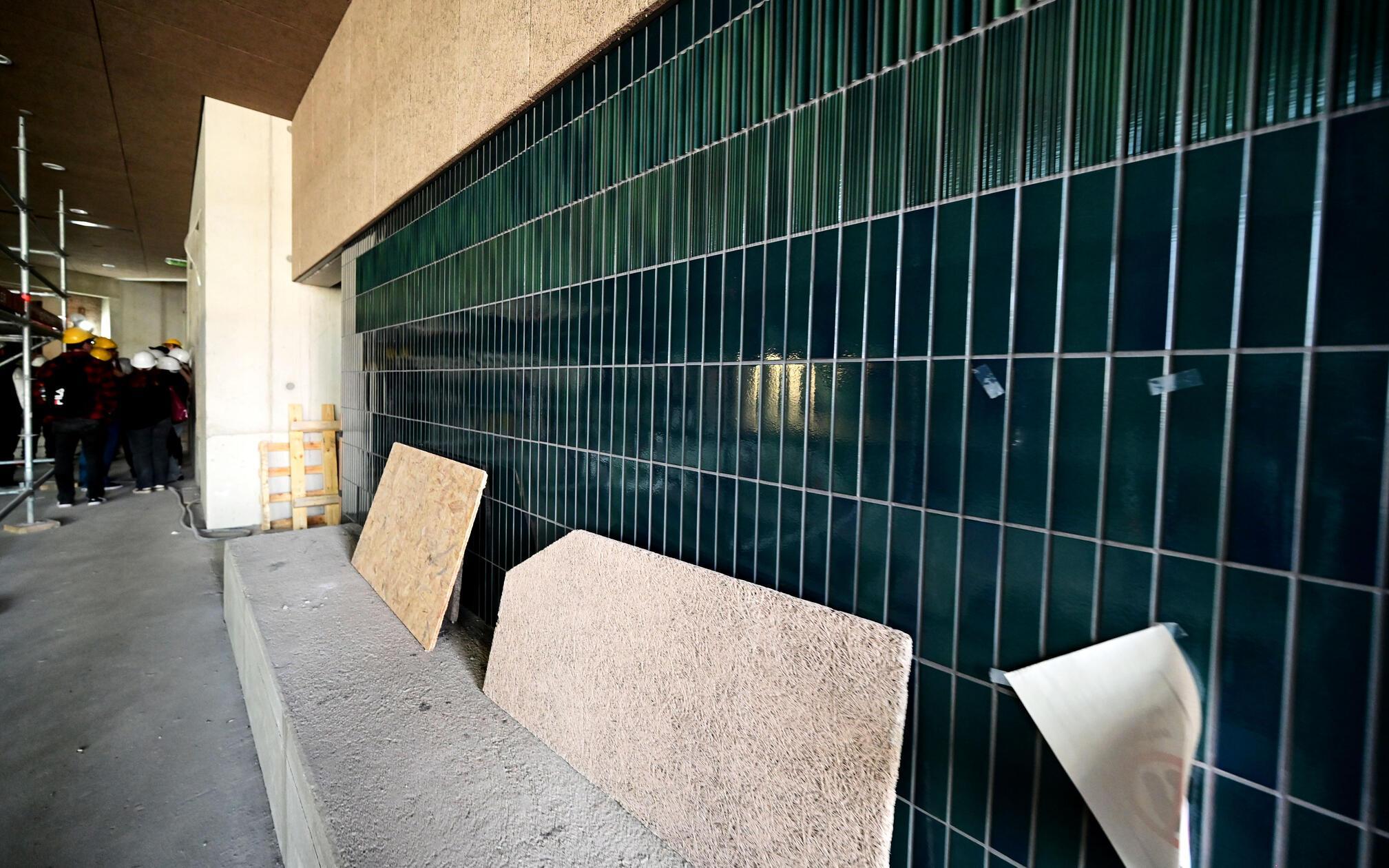 Bis diese Fließen den Weg an die Wand gefunden haben, ist viel Zeit vergangen. Immer wieder hatte sich der Bau verzögert. Das führte auch zu gestiegenen Kosten: Aus ursprünglich 58 Millionen Euro wurden zwischenzeitlich 70 Millionen Euro. Auch der Eigenanteil der statt stieg entsprechend an - von 30 auf 38 Millionen Euro.