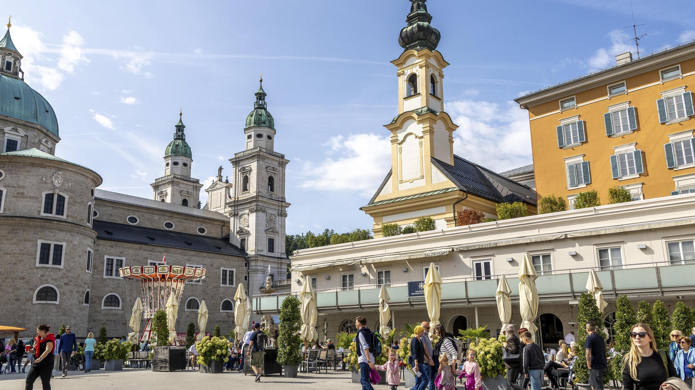 Mozartplatz mit vorbeikommenden Touristen und den 