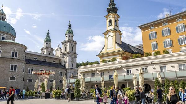 Mozartplatz mit vorbeikommenden Touristen und den