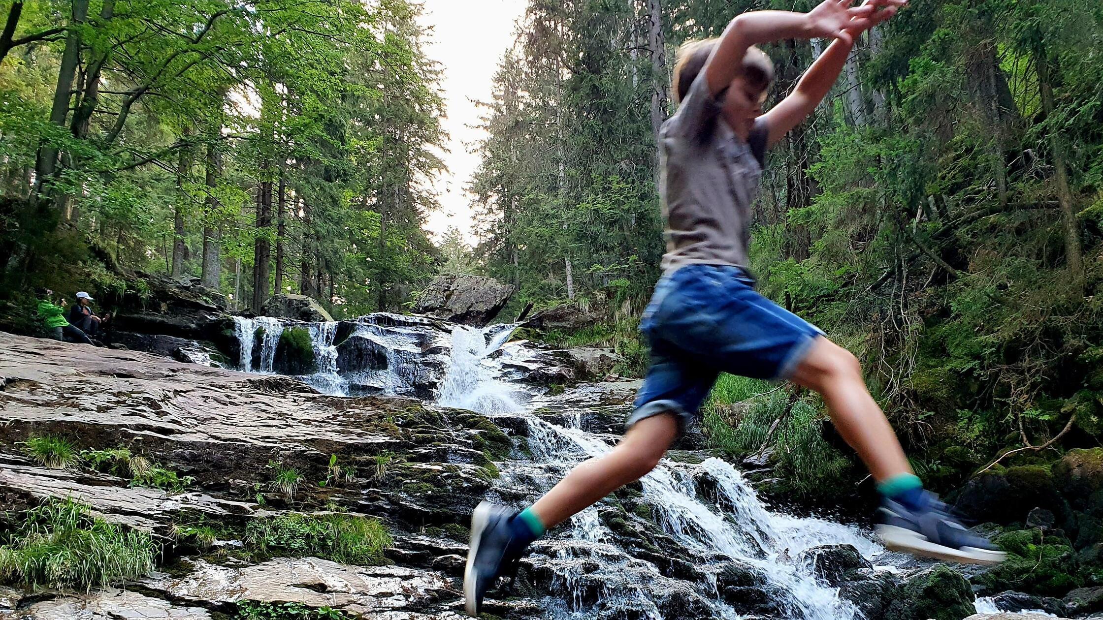 Sprung übers Wasser am höchsten Punkt der Rißlochwasserfälle bei Bodenmais.