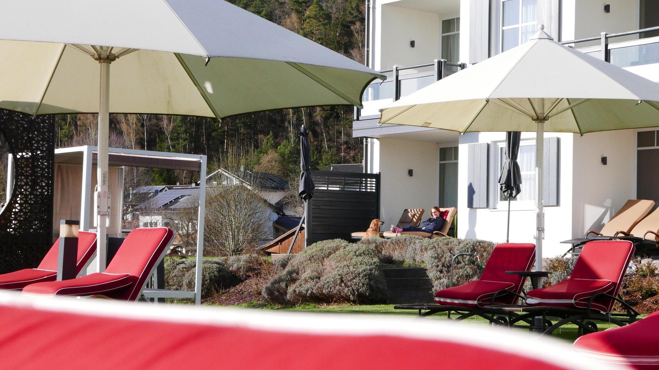 Rote Sonnenliegen am azurblauen Außenpool des Hotels.