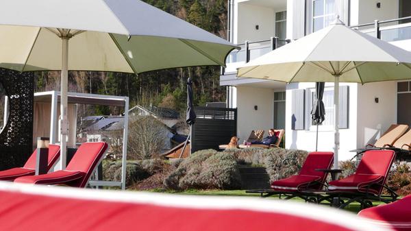 Rote Sonnenliegen am azurblauen Außenpool des Hotels.