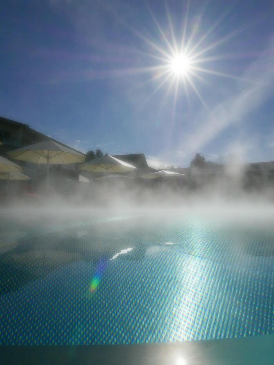 Der dampfende Außenpool bei strahlendem Sonnenschein.