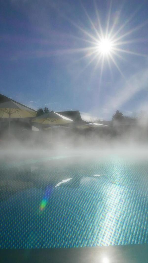 Der dampfende Außenpool bei strahlendem Sonnenschein.