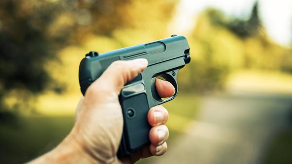 Männerhand mit Waffe, Symbolfoto Kriminalität **