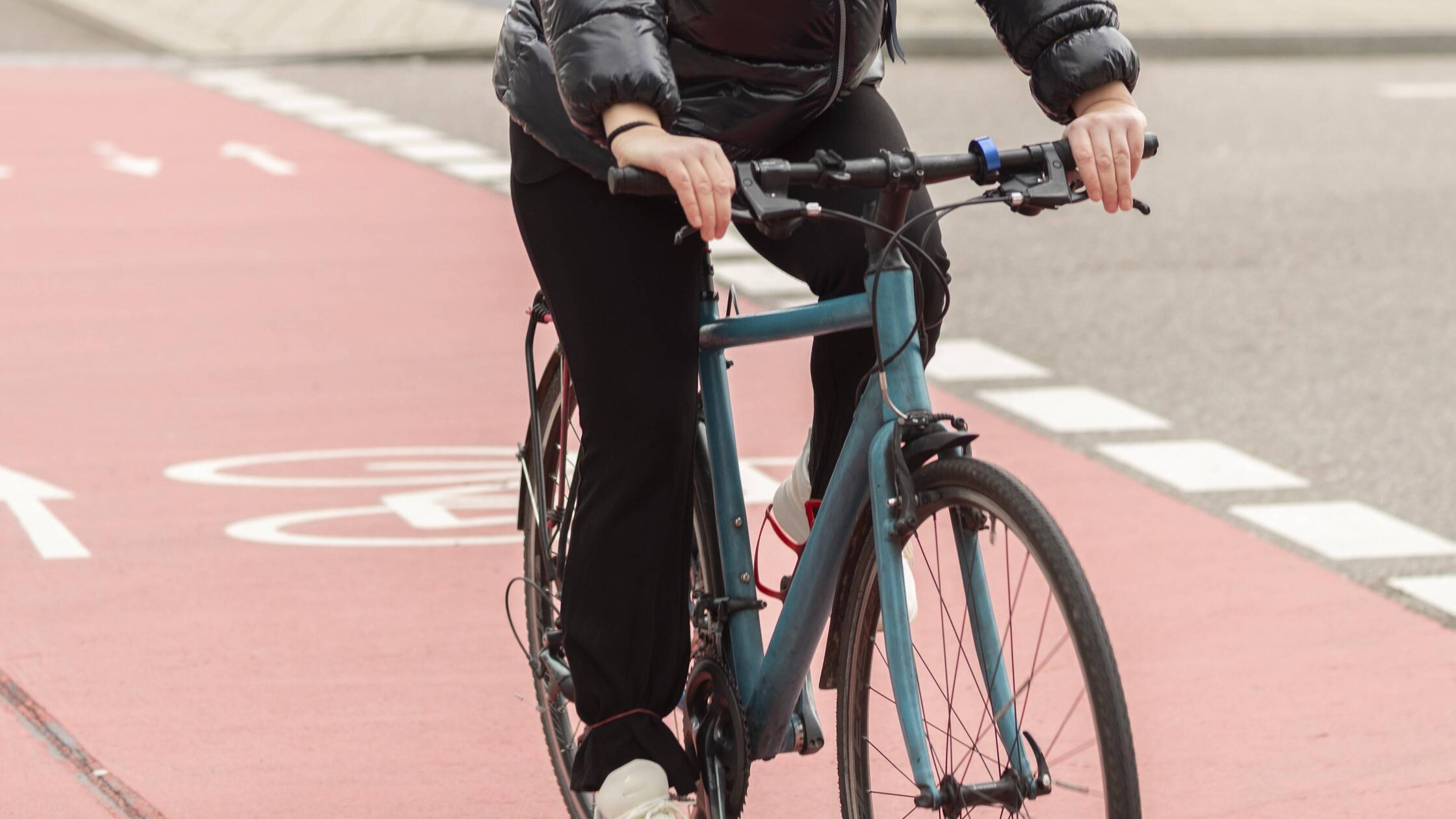 Frau radelt auf einer Straße mit rotem Radweg in e