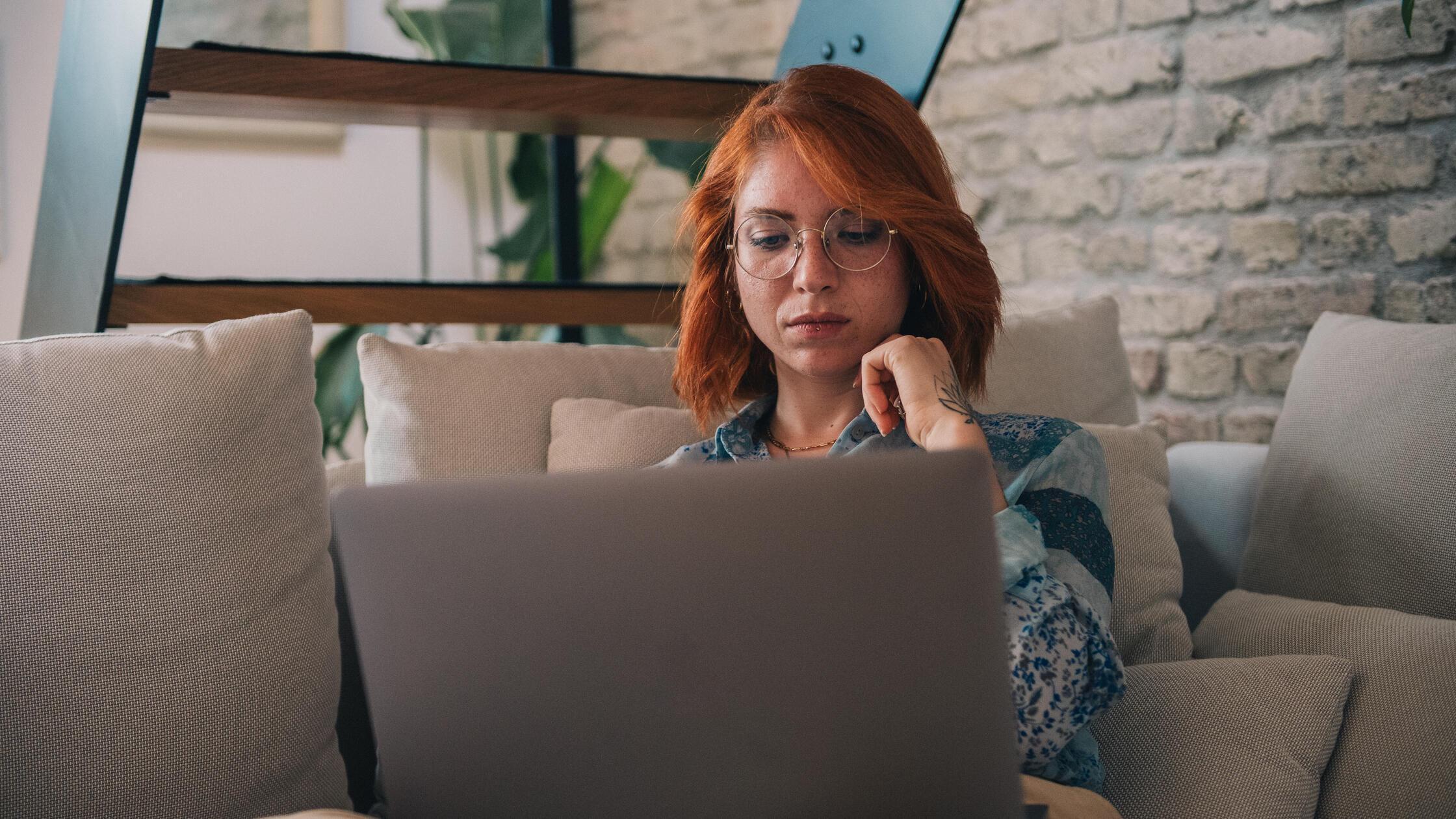 Frau schaut nachdenklich auf einen Laptop