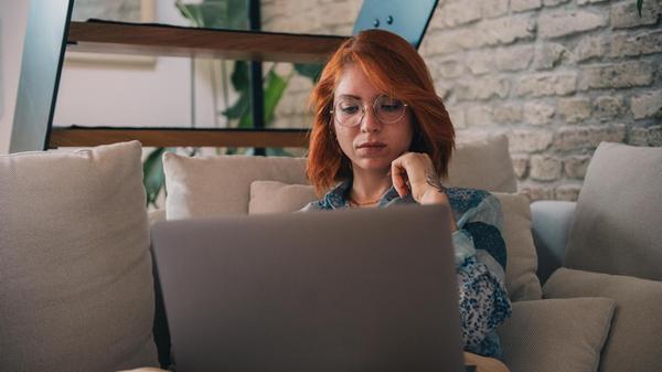 Frau schaut nachdenklich auf einen Laptop