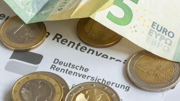 Münzen und eine Banknote liegen auf einer Rentenin
