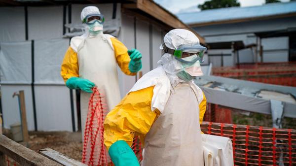 Helfer kommen in Schutzanzügen zu ihrer Schicht in