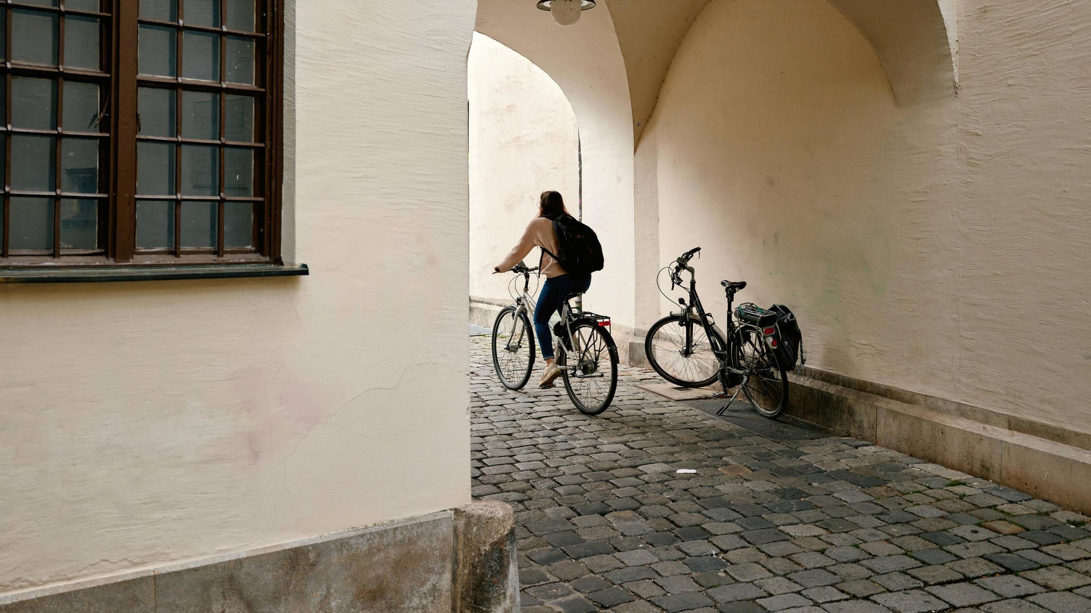 Student cycling through archway in augsburg, germa