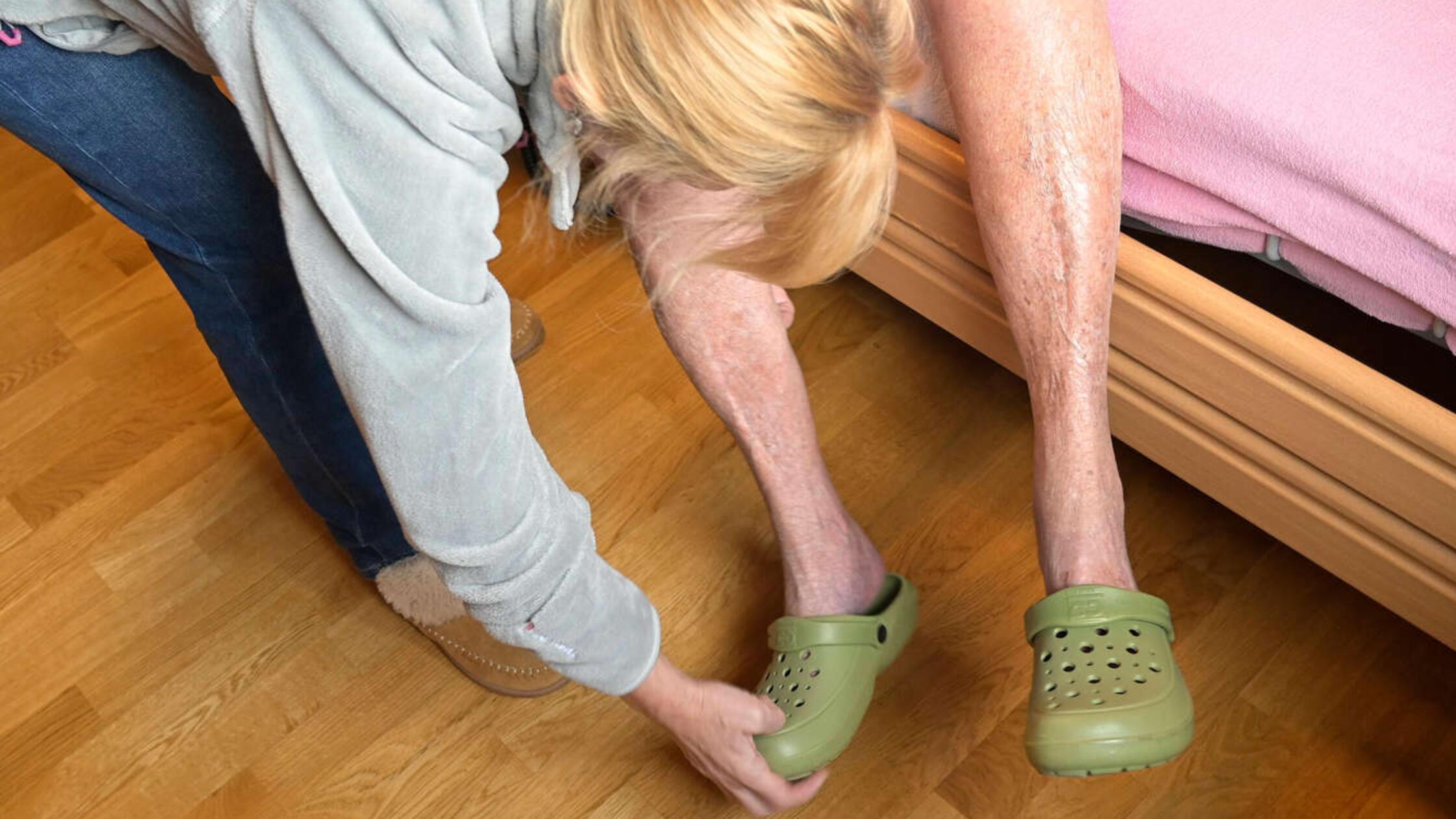 Alte pflegebedürftige Frau braucht Hilfe, Schuhe a