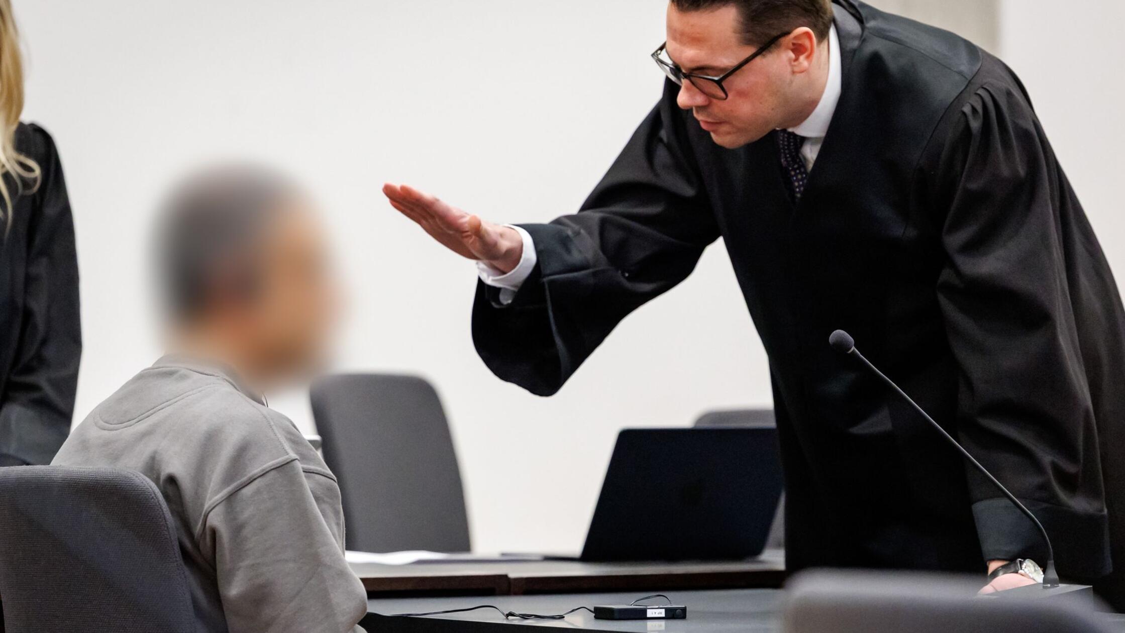 Ein Angeklagter (l) unterhält sich zu Prozessbegin
