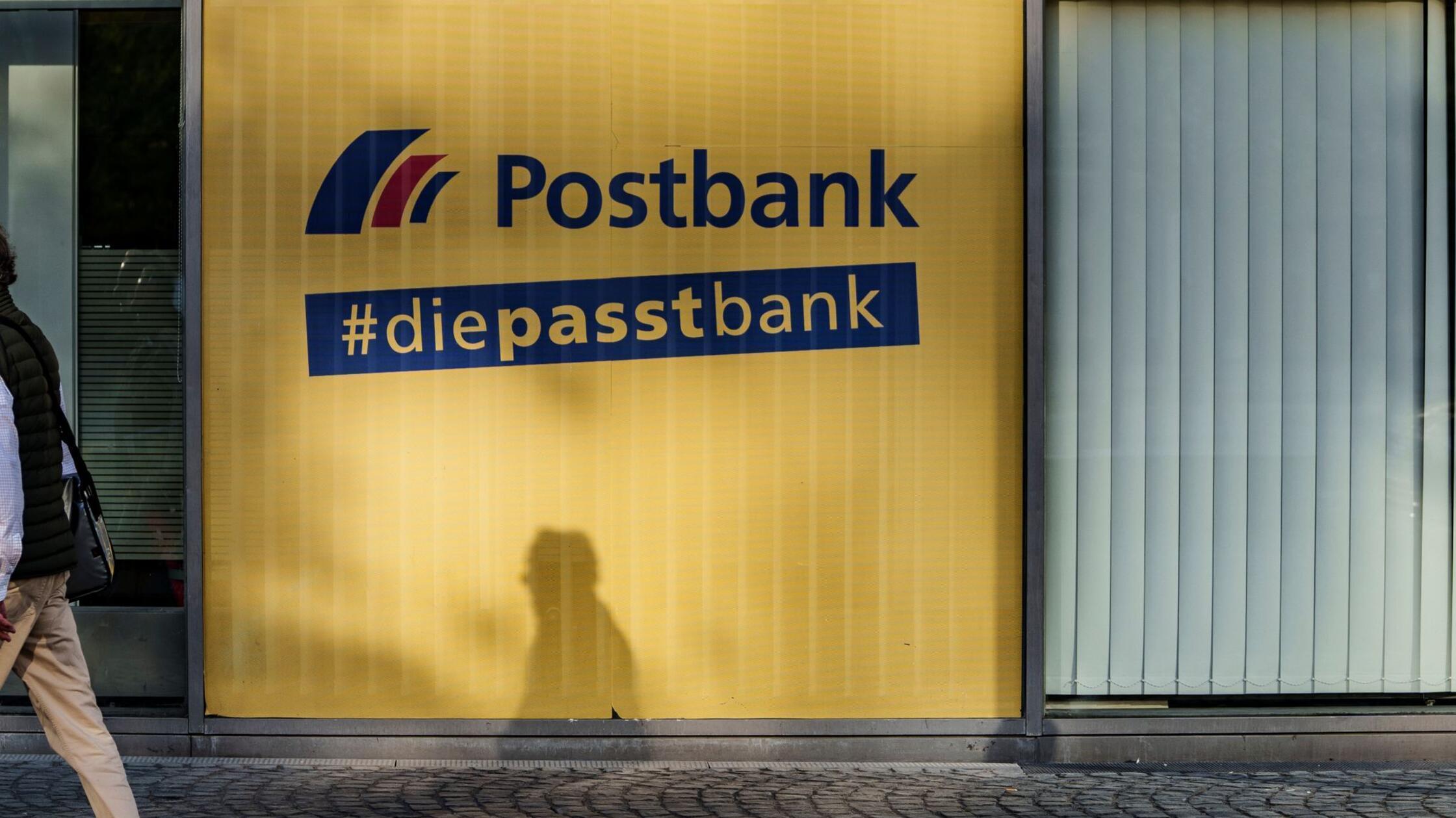 Ein Mann geht an einer Postbank-Filiale vorbei. (z