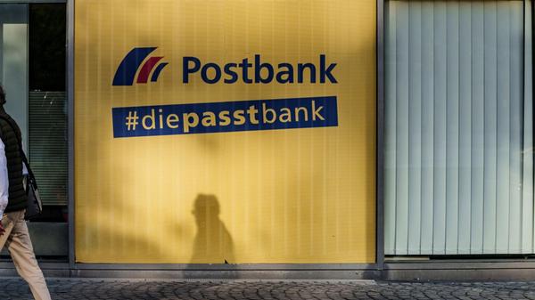Ein Mann geht an einer Postbank-Filiale vorbei. (z
