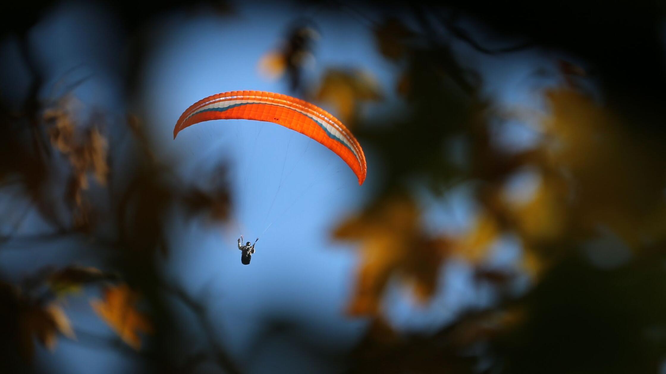 Ein Gleitschirmflieger schwebt am wolkenlosen Himm