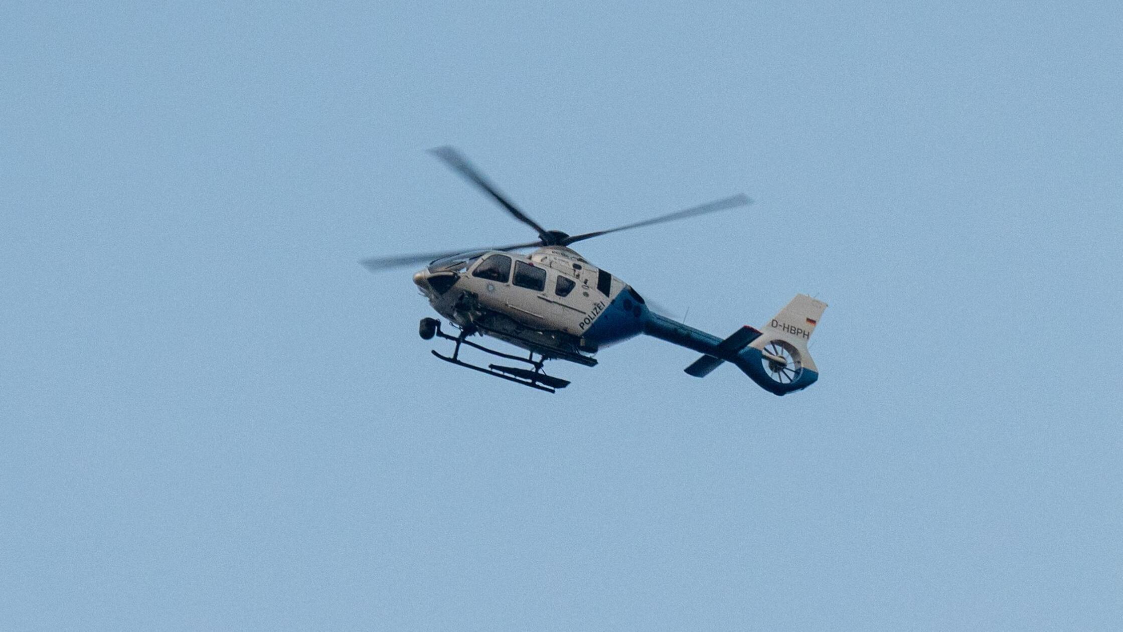 Ein Polizeihubschrauber fliegt über den Ortsrand. 